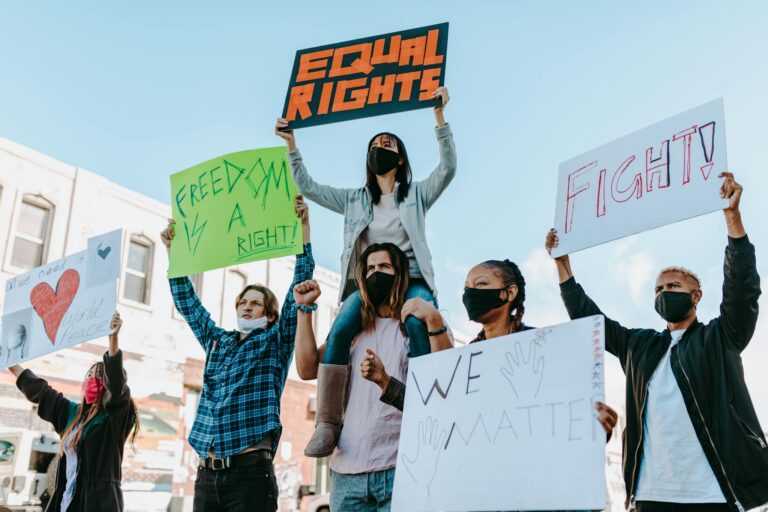 A diverse group of protesters holding signs advocating for equal rights and freedom on a street.