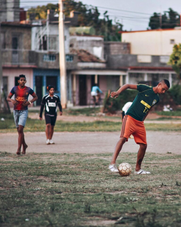 Boys playing soccer on a local dirt field in a residential neighborhood.