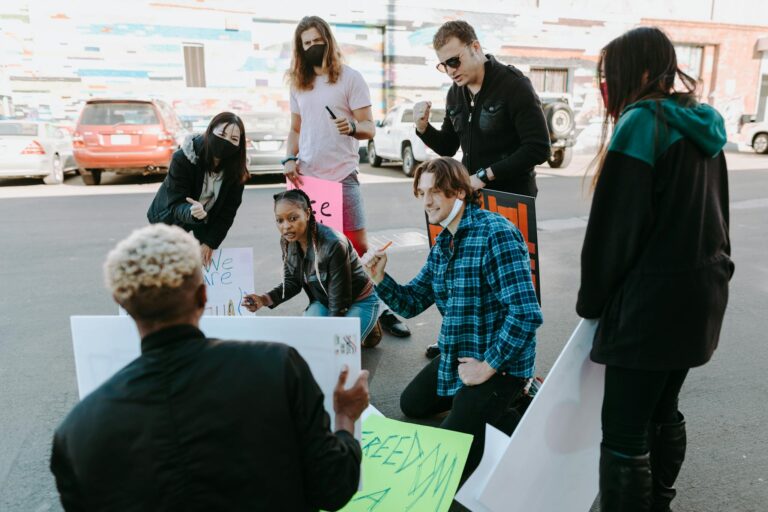 Diverse group of activists preparing protest signs outdoors, signifying unity and activism.
